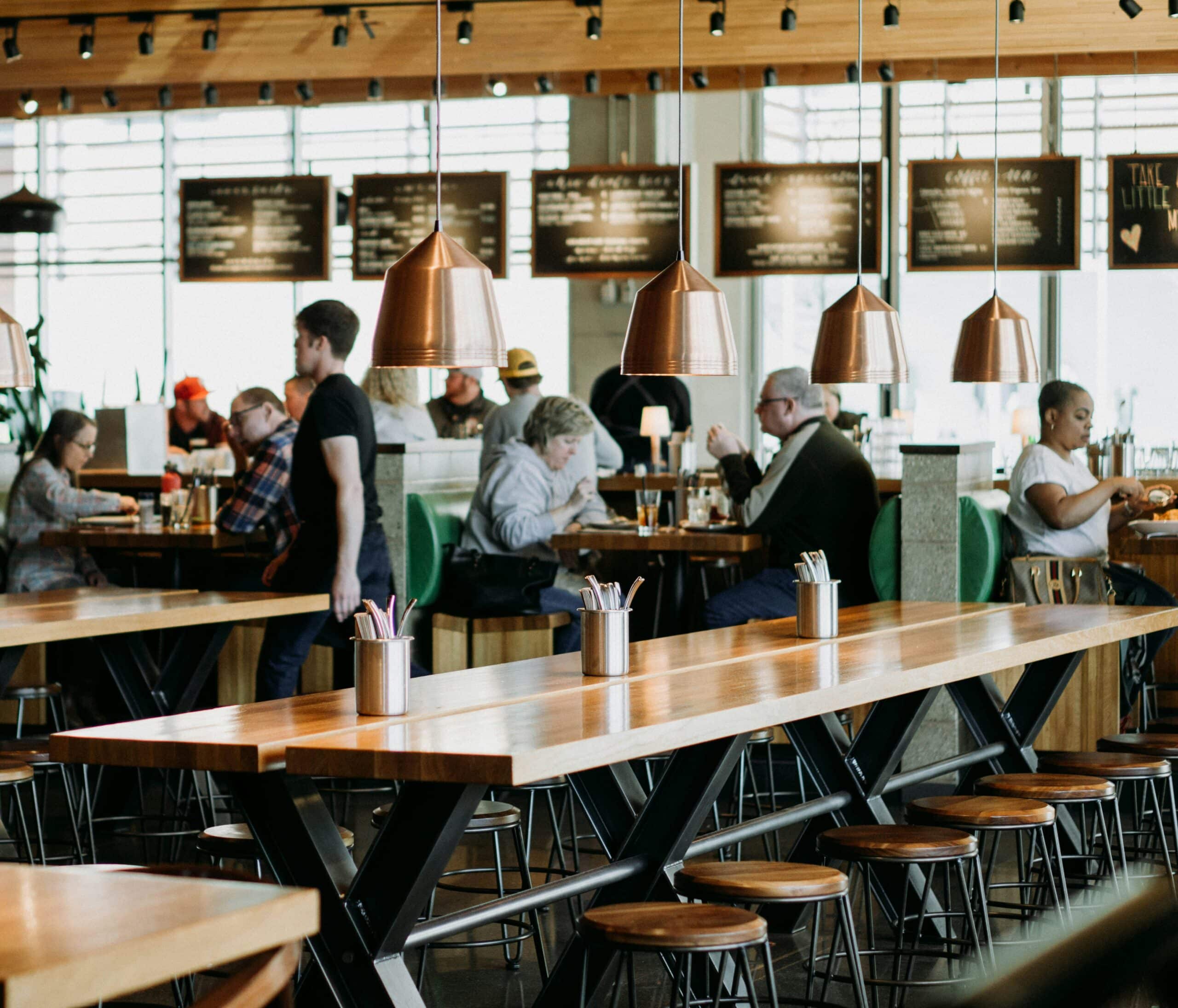 Modern restaurant interior with customers dining and staff serving, showcasing a casual and welcoming atmosphere.